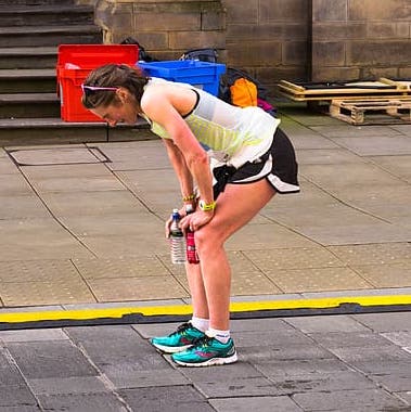 woman-holding-knees-with-both-hands-while-on-a-pathway