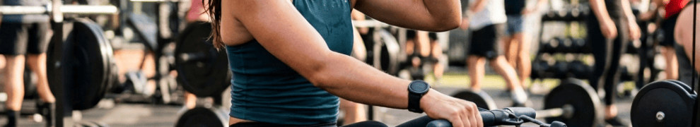 Woman drinking water while seated at an outdoor rowing machine